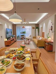 a dining room table with many plates of food on it and a flat screen tv in the background