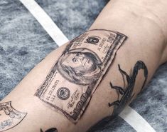 a person with a tattoo on their arm has a dollar bill in the shape of a man's head