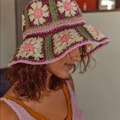 a woman wearing a crocheted hat with flowers on it