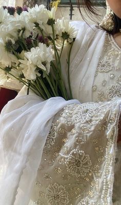 a bouquet of white flowers sitting on the back of a bride's wedding dress