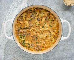 a pot filled with pasta and mushrooms on top of a table