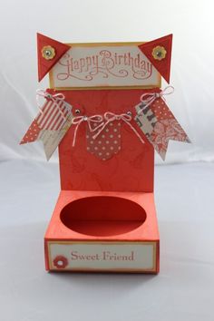 an open red box with some tags on it and a happy birthday sign hanging from the top