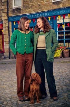 two women standing next to each other in front of a store with a brown dog