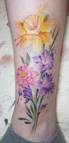 a woman's leg with flowers painted on it and watercolors in the background