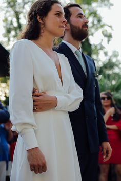 a woman in a white dress standing next to a man in a suit and tie