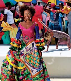 a woman in a colorful dress standing next to a painting