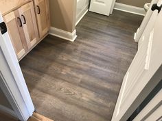 an empty kitchen with wood floors and white cabinets in the backround, looking into the pantry area