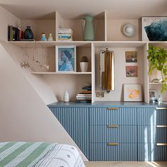 a bedroom with blue dressers and shelves filled with books, vases and pictures