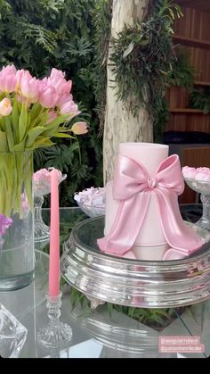 a table topped with a cake covered in pink ribbon and flowers on top of it