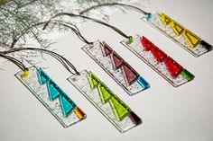 four pieces of colorful glass sitting on top of a white table next to a tree