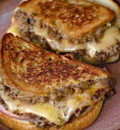 two grilled cheeseburgers on a plate with meat and melted cheese in the middle