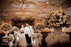 the bride and groom are walking down the aisle in their wedding ceremony attire with flowers on either side