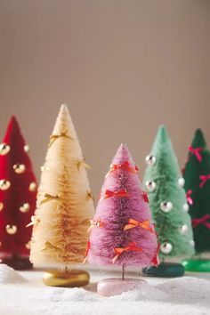 small christmas trees are lined up on a table with white snow and gold trimmings