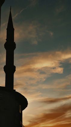 the silhouette of a clock tower against a sunset sky with clouds in the back ground