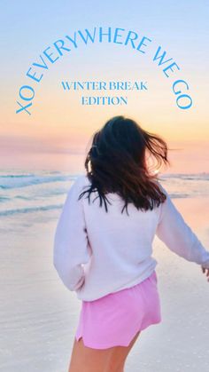 a woman walking on top of a beach next to the ocean with her back to the camera