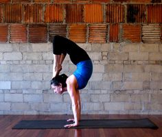 a woman is doing yoga on a mat in front of a brick wall and wooden floor