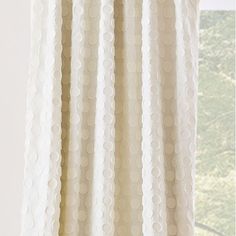 a white curtain hanging on the side of a window sill in front of a window