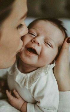 a woman kissing a baby with her mouth open