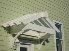 an outside view of a green house with a white awning over the door and windows