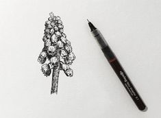 a drawing of a pine tree on paper next to a marker with the ink pen in it