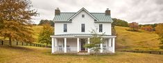 a white house sitting on top of a lush green hillside