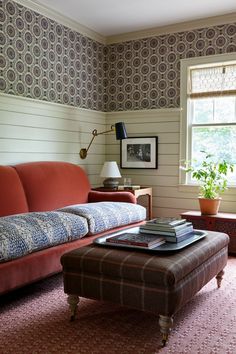 a living room with a couch, ottoman and table in front of a large window