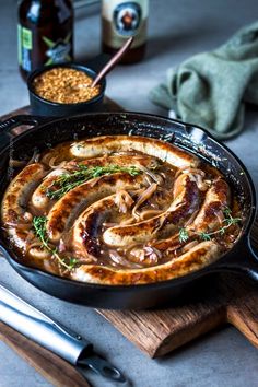 a skillet filled with food sitting on top of a wooden cutting board next to a bottle