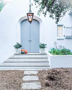 a white house with steps leading to the front door and potted plants on either side