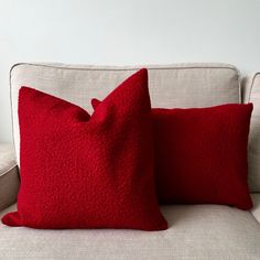 two red pillows sitting on top of a white couch