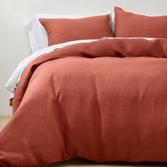 a bed with an orange comforter and white sheets