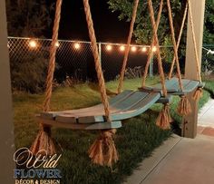 a wooden swing with lights hanging from it's sides in front of a house