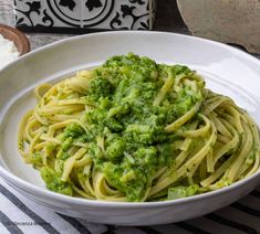 a white bowl filled with pasta and broccoli on top of a striped table cloth