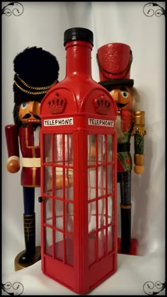 a red telephone booth with two nutcrackers and a toy soldier next to it