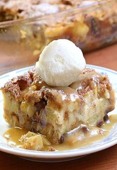 a piece of bread pudding with ice cream on top sits on a plate next to a casserole dish