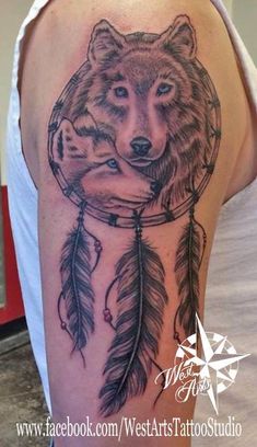 a woman's arm with a wolf and feathers tattoo on the back of her shoulder