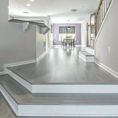 an empty living room with stairs leading up to the dining room table and bar area