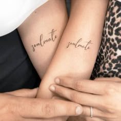 two people with matching tattoos on their arms, one is holding the other's arm