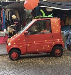 a small red car with yellow polka dots on it's side in front of a store