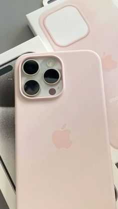 two pink iphones sitting next to each other on top of a white box with an apple logo