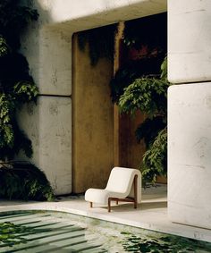 a white chair sitting next to a pool in front of a building with ivy growing on it