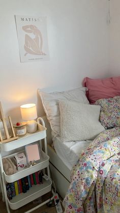 a white bed topped with lots of pillows next to a night stand filled with books