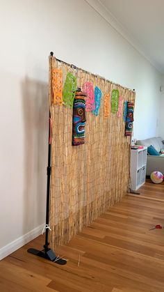 a room with wood floors and a wall decorated with tiki masks on it's side