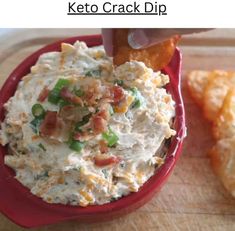 a red bowl filled with potato salad next to crackers