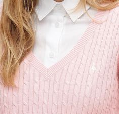 a woman with long hair wearing a blue sweater and white collared shirt is looking at the camera