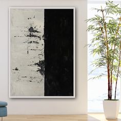 an abstract painting hangs on the wall next to a chair and potted bamboo plant