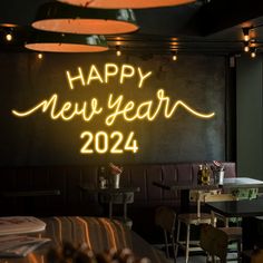 a neon sign that says happy new year next to tables and chairs in a restaurant