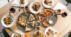 a table topped with lots of different types of pizzas and plates filled with toppings