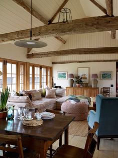 a living room filled with lots of furniture and wooden beams on top of the ceiling