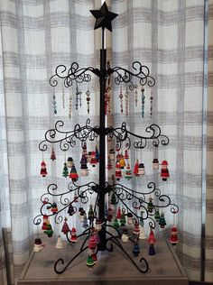 a christmas tree made out of ornaments on a table in front of a curtained window