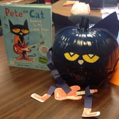 a cat pumpkin sitting on top of a wooden table next to a bookshelf